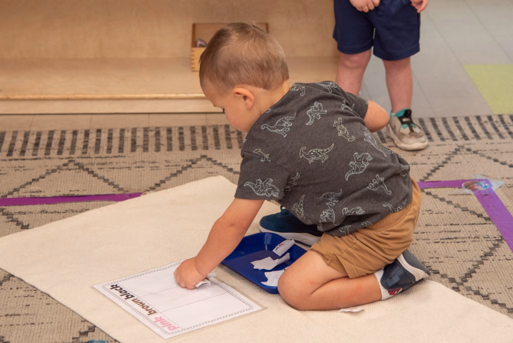 Two-year-old practicing independence in Montessori toddler environment